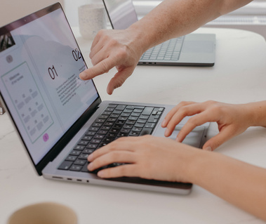 hands pointing at the computer screen and other hands typing on the computer keyboard 