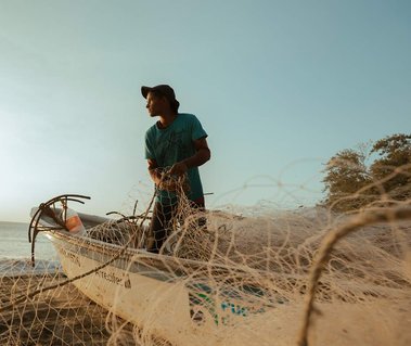 young fisherman in his boat pulling fishing net