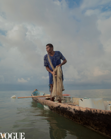 Fisherman fishing in his boat with fishing net in his mouth