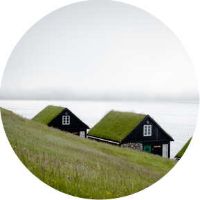 Two houses with the thatched roof standing by a misty sea.