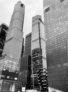The Vessel hidden between scyscrapers. Hudson Yards, New York City. B&w photography of architecture.
