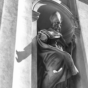 Marble statue of saint in the church arcade. Rome, Italy. B&w photography.