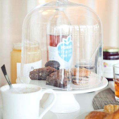 muffins et bouteille de jus de pomme sur table sous une cloche de verre avec croissant et café