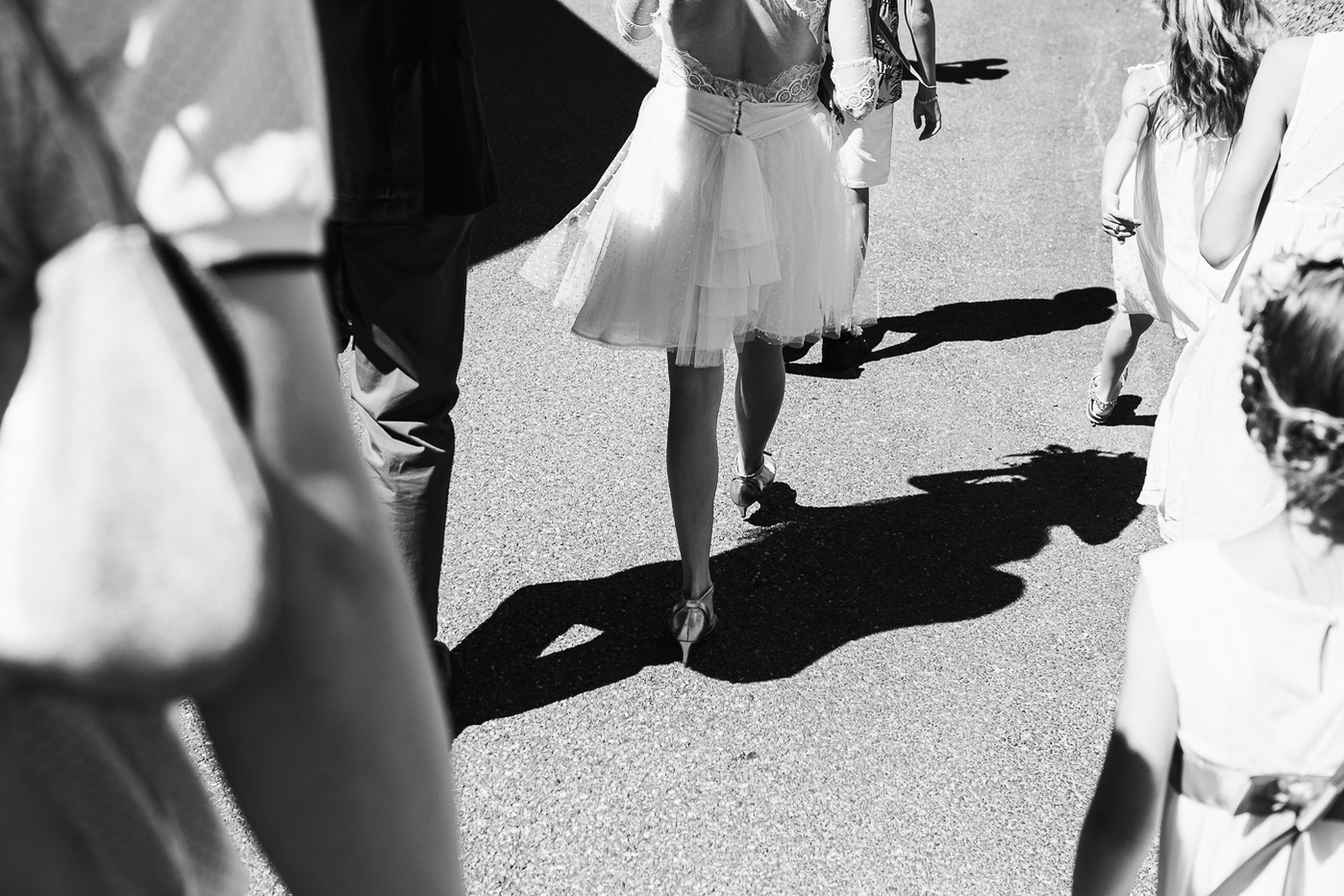 robes et jambes d'une mariée marchant au milieu d'un groupe