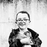 garçon en noir et blanc avec une poule dans les bras