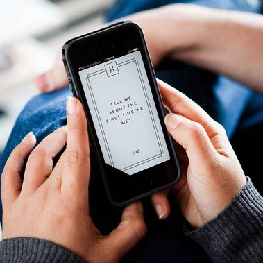 Hands hold an iPhone using {THE AND} app and question appears on the screen 