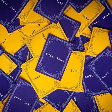 Yellow and purple {THE AND} playing cards are spread out on a table.
