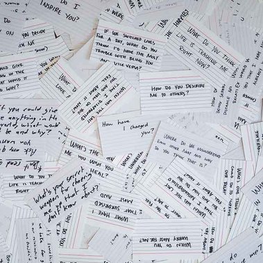 Handwritten questions on index cards are spread out on a table
