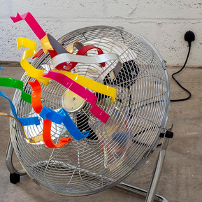Acrylic ribbons attached to a fan that is off with the plug directly in the wall