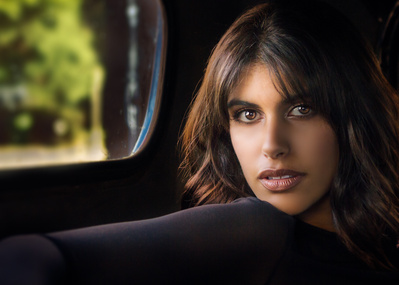 Headshot of a brunette sitting in truck with light coming in through the window.