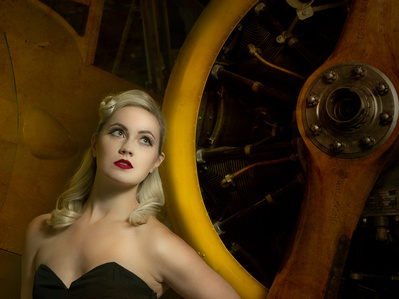 Attractive blonde female leaning on yellow airplane propeller