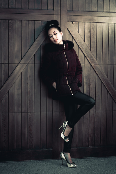 Woman in dark winter coat leaning against a wooden door