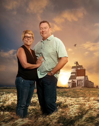 A composite portrait of a couple in a field of grass with a grain elevator in the background and a sunset sky