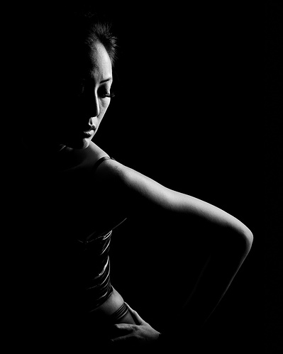 A low-key black-and-white portrait of a young lady.