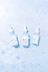 The Ordinary Deciem X Scott Uzoho -- product still-life photography of beauty skin care products over water droplets 