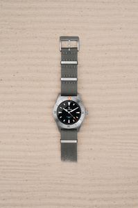 Belhamel X Scott Uzoho -- product still-life photography of swiss watch panically covered over sand with horizontal line pattern 