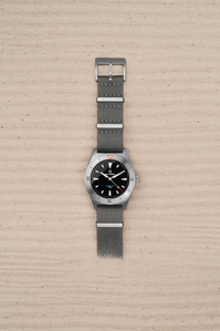 Belhamel X Scott Uzoho -- product still-life photography of swiss watch panically covered over sand with horizontal line pattern 