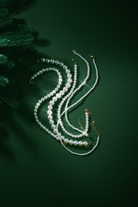 Ventr X Scott Uzoho -- product still-life photography of shining pearls on emerald green background with foliage and shadows 