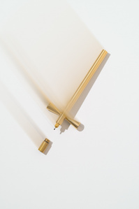 Toms Studio X Scott Uzoho -- product still-life photography of golden Brass fineline pen artist tools with smudge effect creating motion 