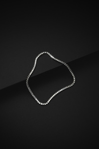 Ventr X Scott Uzoho -- product still-life photography of a silver tennis necklace perched on 2 black slates 