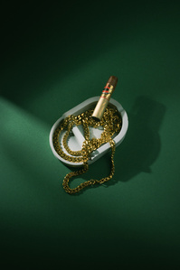 Ventr X Scott Uzoho -- product still-life photography of gold chains in ashtray with light reflections and cigar 