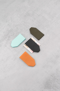 Kristopherstore X Scott Uzoho -- product still-life photography of leather coloured money clip in pattern formation on light concrete 