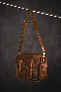 Kalting Bags X Scott Uzoho -- product still-life photography of leather luggage on concrete set dangling from stainless steel pole showing shoulder strap 