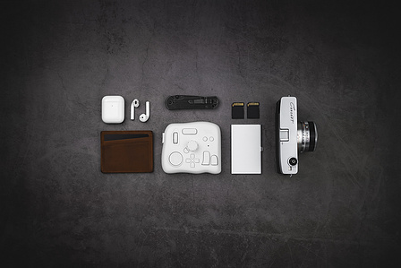 Tourbox X Scott Uzoho -- product still-life photography of editing, camera, canon cannot, leather bullstrap, AirPods apple and memory sd cards in a everyday carry style flatlay 