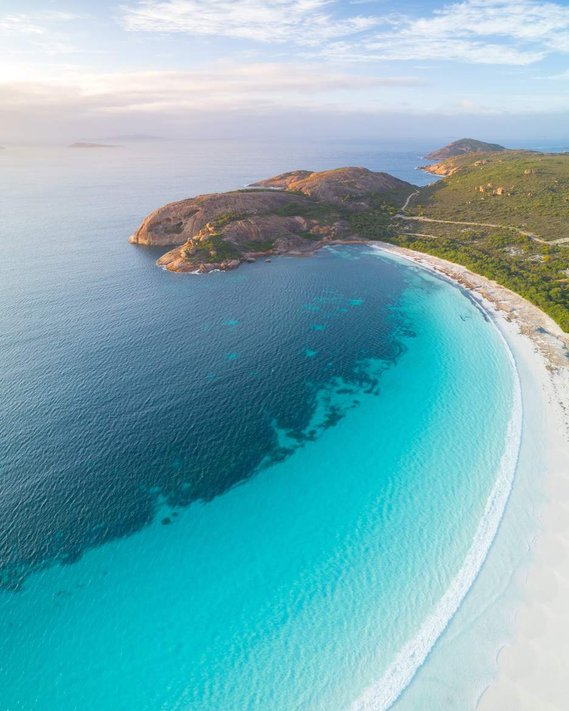 A beach in Australia with large hills in the distance.