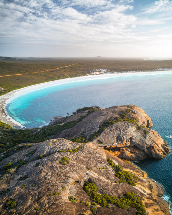 A large rock formation on the edge of a beach in Australia.