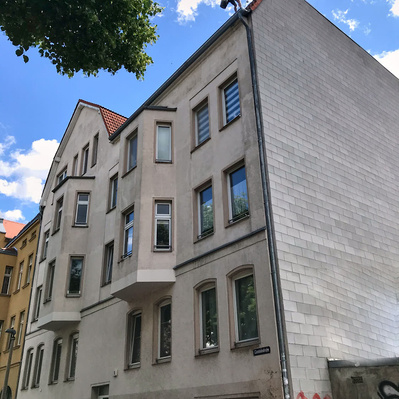 Ein Höhenarbeiter steht auf einem Hausdach in Halle (Saale) und begutachtet das Dach. 