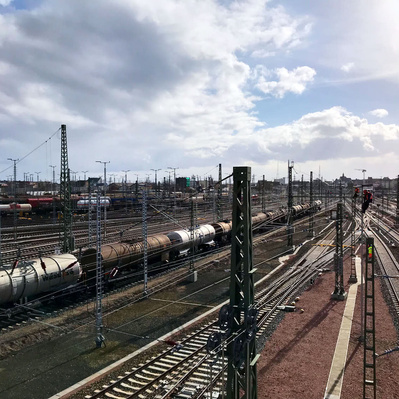 Zwei Arbeiter begutachten die Lampen auf dem Bahnhofsgelände. Dokumentation und Protokoll