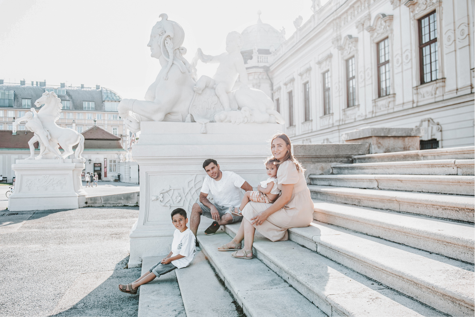Familie sitzt auf der Treppe in Wien an einem sonnigen Tag