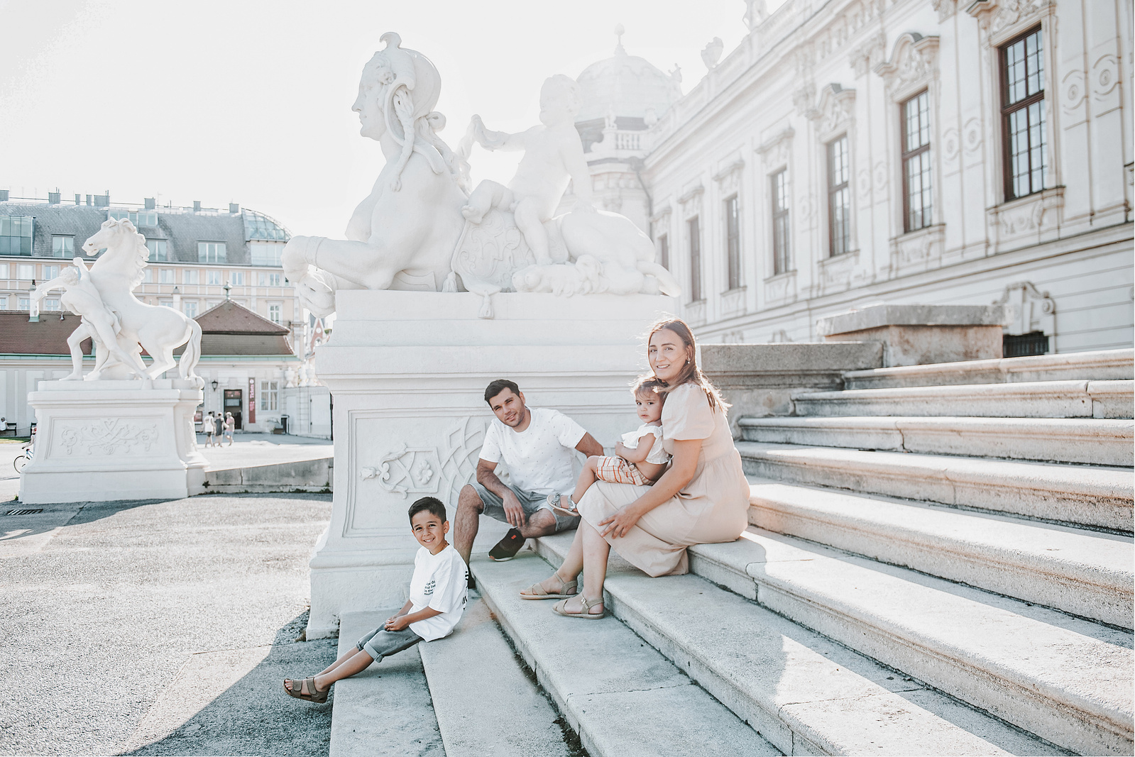 Familie sitzt auf der Treppe in Wien an einem sonnigen Tag