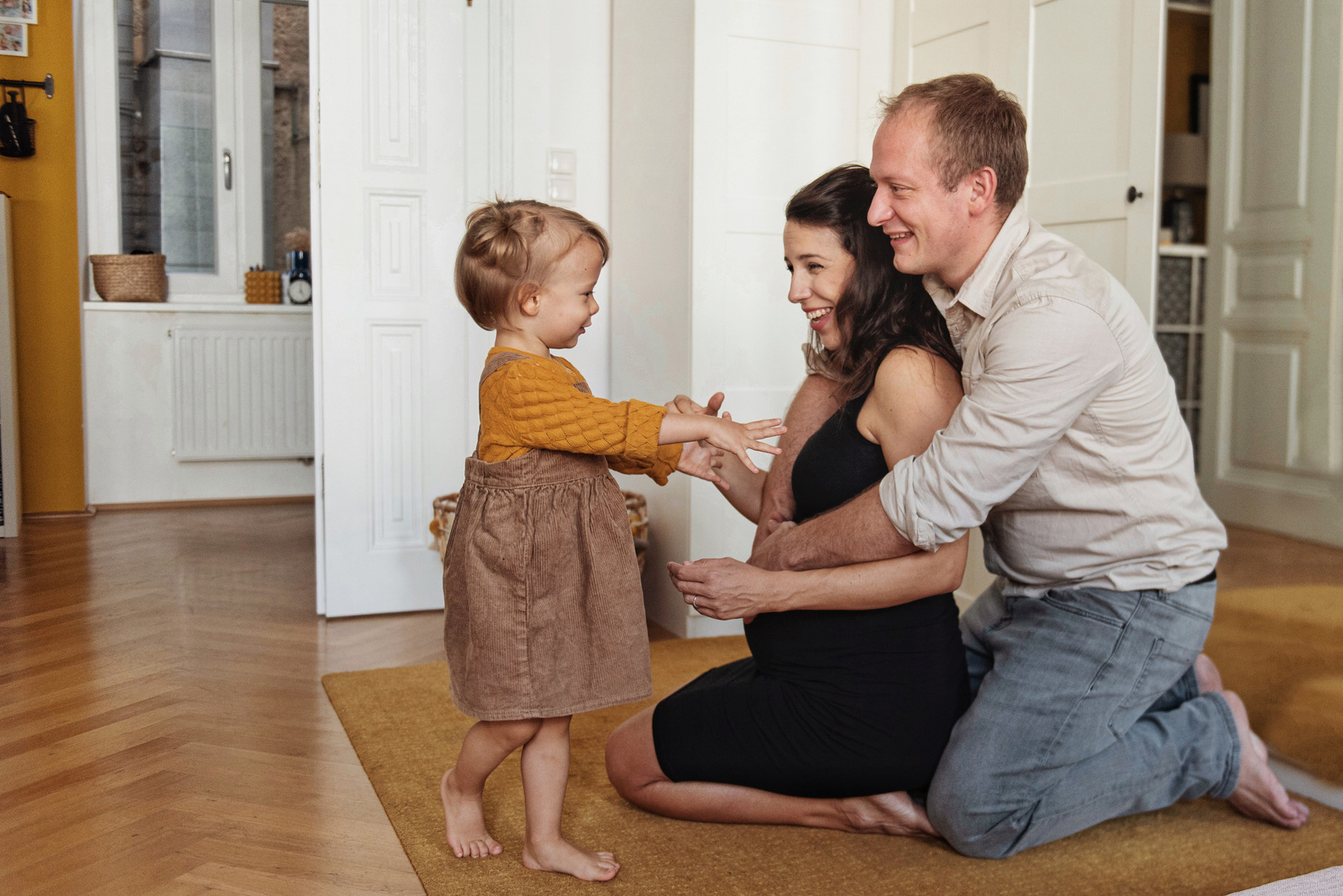 Mutter mit Babybauch und Vater spielen zu Hause mit Kind