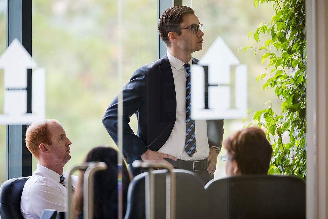 Photo of two men in an investment meeting, inside a conference room. There are logos of Hennessy Funds on the conference room windows.