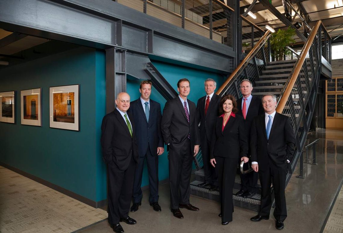 Formal group portrait of seven executives standing on the stairs in their shipping company headquarters.