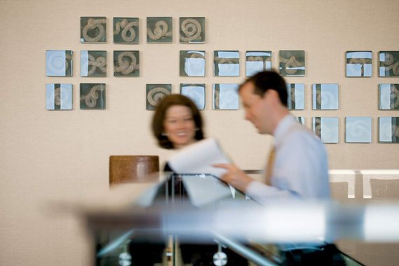 Photo of two office workers walking up the stairs and having a conversation. The environment is sharp, while their bodies are motion blurred.
