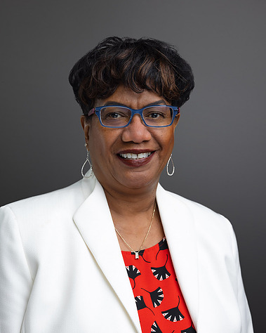 Formal portrait of a Wealth Manager from First Republic Bank against a gray background. The photographic lighting on the face is considered 