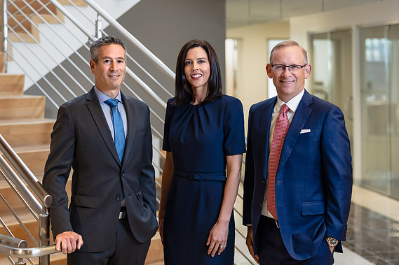 Formal 3-person team/group shot of wealth managers at a First Republic Bank in San Francisco, California. The team members are posed in front of a large staircase.