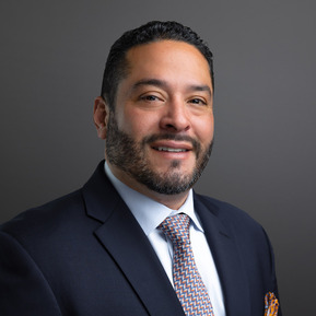 Formal portrait of a Wealth Manager from First Republic Bank against a gray background. The photographic lighting on the face is considered 
