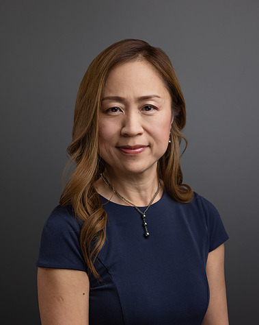 Formal portrait of a Wealth Manager from First Republic Bank against a gray background. The photographic lighting on the face is considered 