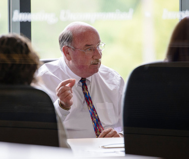 Office lifestyle portrait of an executive man in a meeting. Outside the office window is an out-of-focus city of Novato, California, trees, and other greenery.