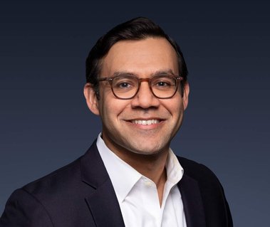 Color portrait of an investment banker against a blue, seamless background