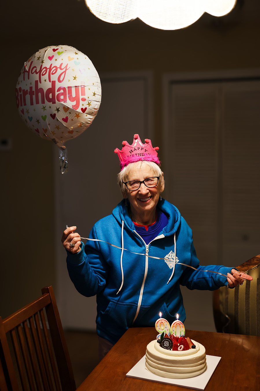 A colorful birthday cake topped with fruit, lollipops, and “Happy Birthday” candles, perfect for senior celebration photography and family event moments.