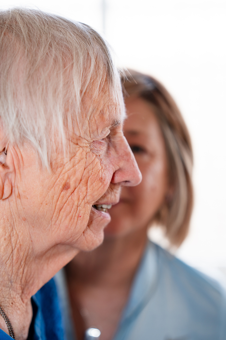 A tender profile portrait of a senior woman and her adult daughter sharing a quiet, intimate moment that highlights generational connection and family closeness.