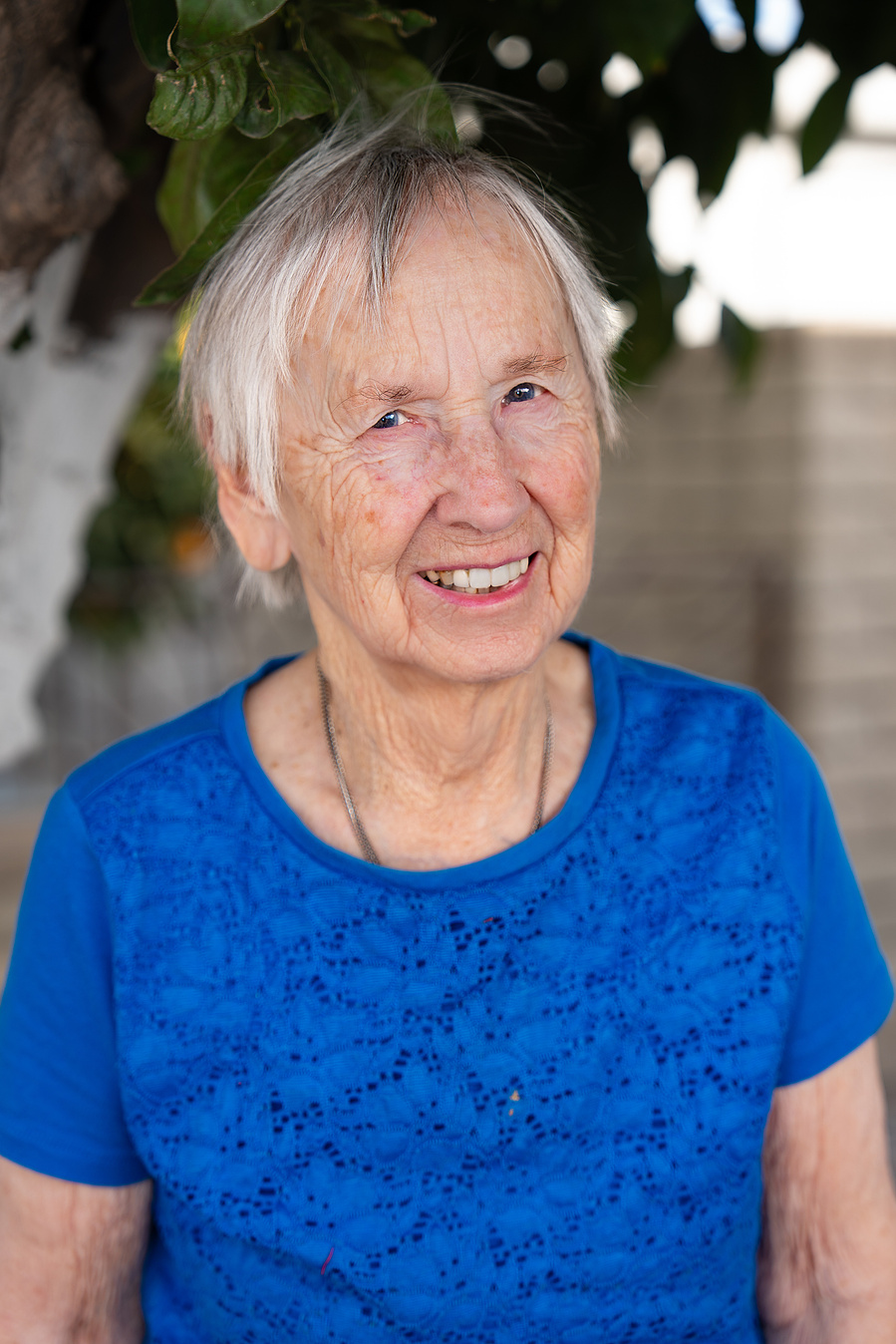 This candid portrait of a happy elderly woman under a tree highlights vibrant senior living and the beauty of aging with joy and simplicity.