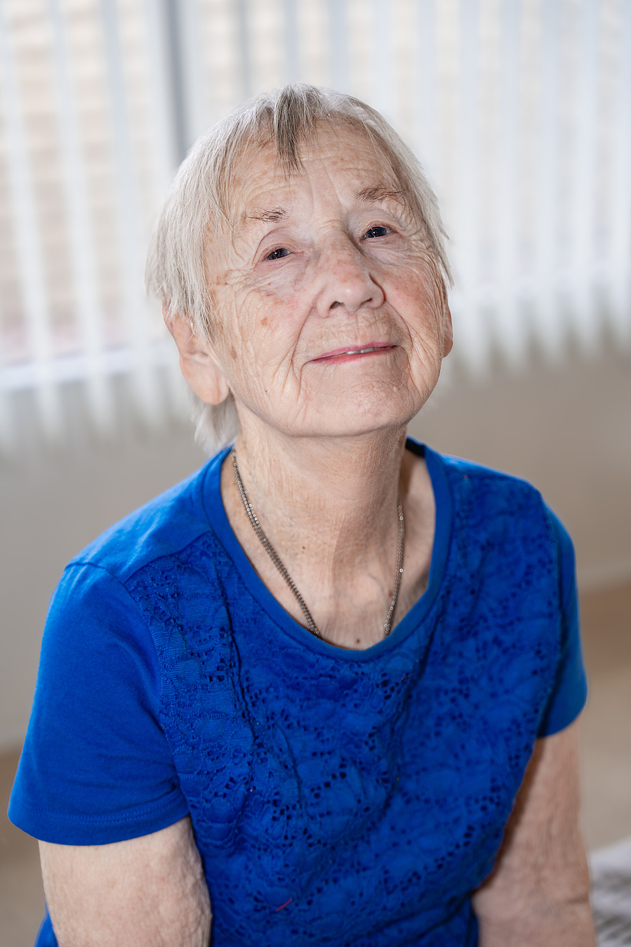 A confident 90-year-old woman looks upward with a serene expression, representing strength, wisdom, and timeless beauty in senior photography.