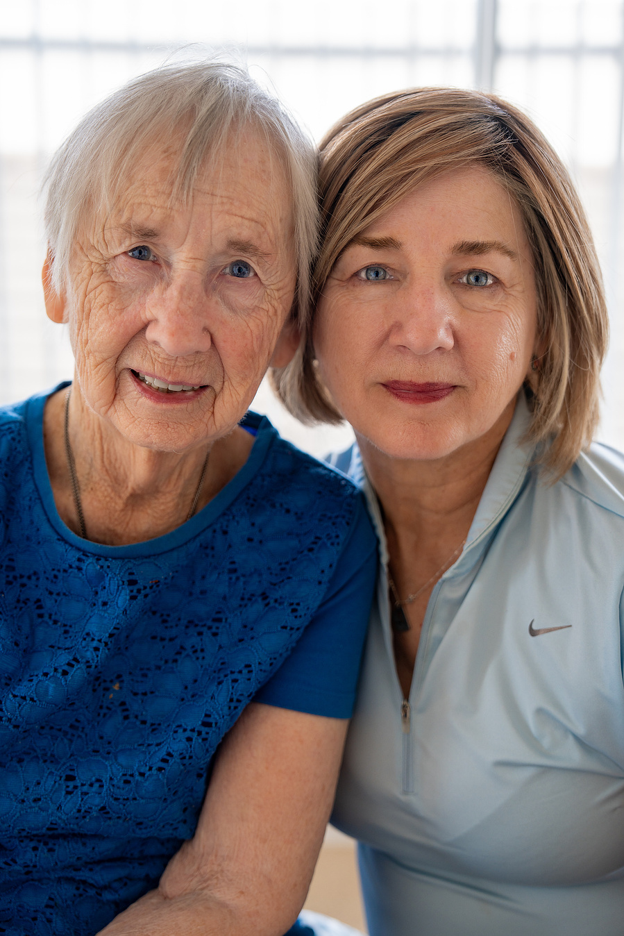 This senior portrait captures a joyful 90-year-old woman with her daughter, reflecting strong family bonds and loving generational relationships.