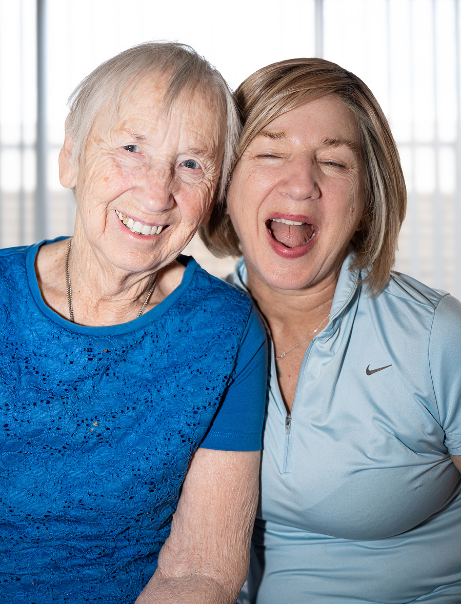 A candid, fun-filled photo of a senior woman and her daughter laughing together, emphasizing genuine emotion and joyful aging in family portraits.